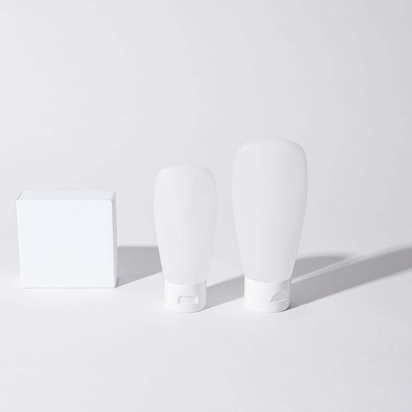 Unbranded white body care bottles on a pale grey background
